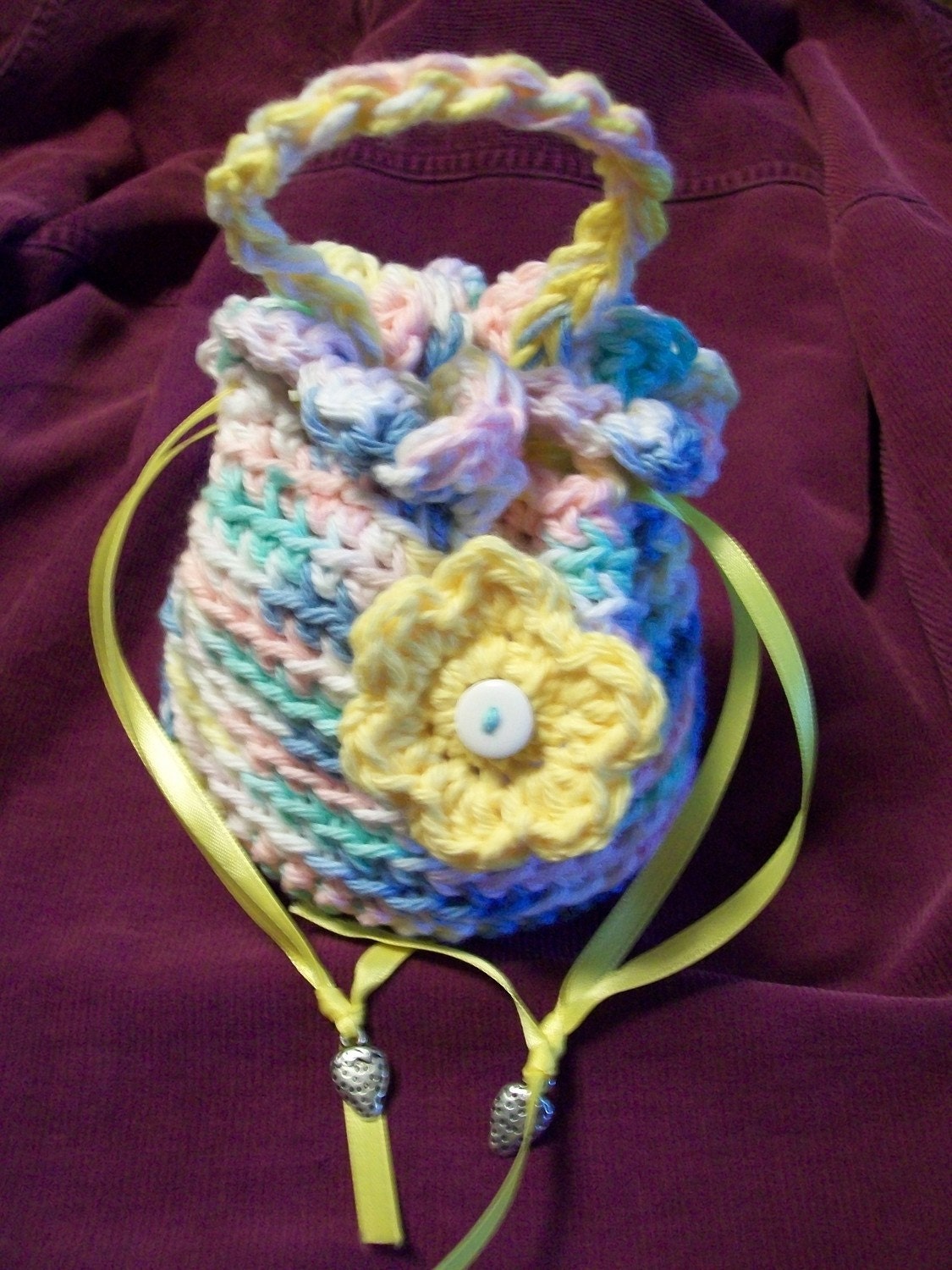 Girl's drawstring crocheted purse in pastel colors with flower.