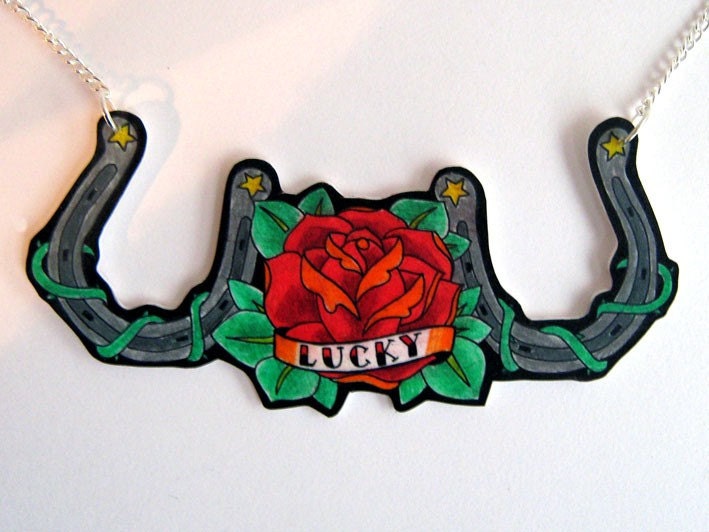 Two horseshoes with a rose in the centre, which has a tattoo style banner 