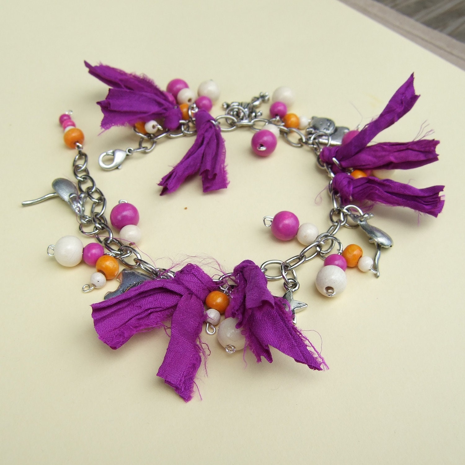 Purple sari ribbon, white, orange and deep pink wood beads, charms and chain bracelet